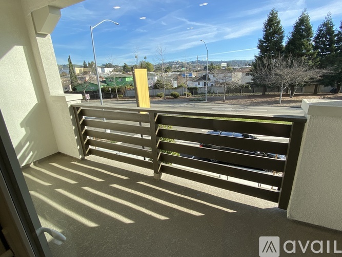 A balcony with a view of a parking lot and trees.