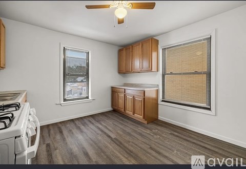 A kitchen with a white stove top oven and wooden cabinets.