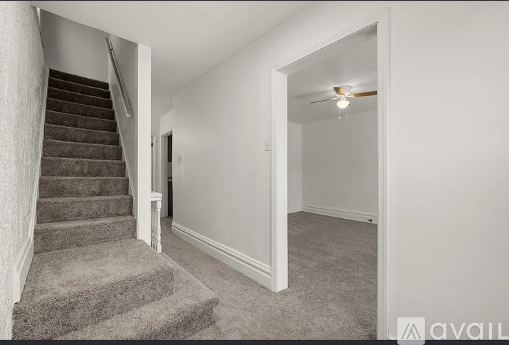 A staircase with a carpeted runner leads up to a white door.