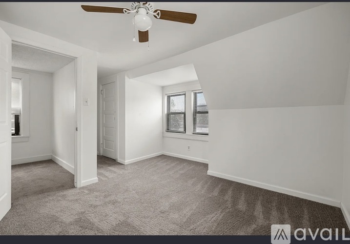 A spacious room with a ceiling fan and carpeted floor.