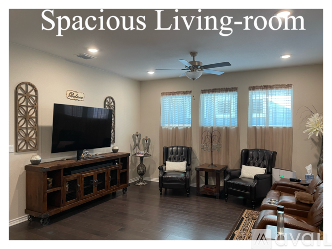 A spacious living room with a television, two chairs, and a table.