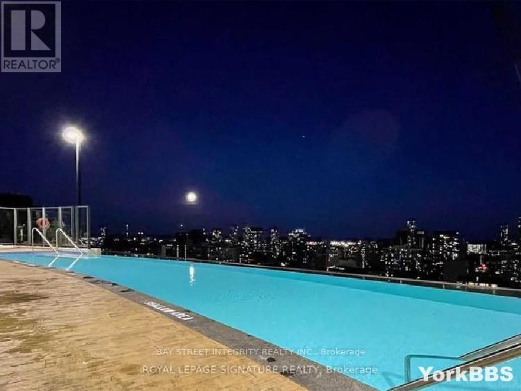 A pool at night with a cityscape in the background.