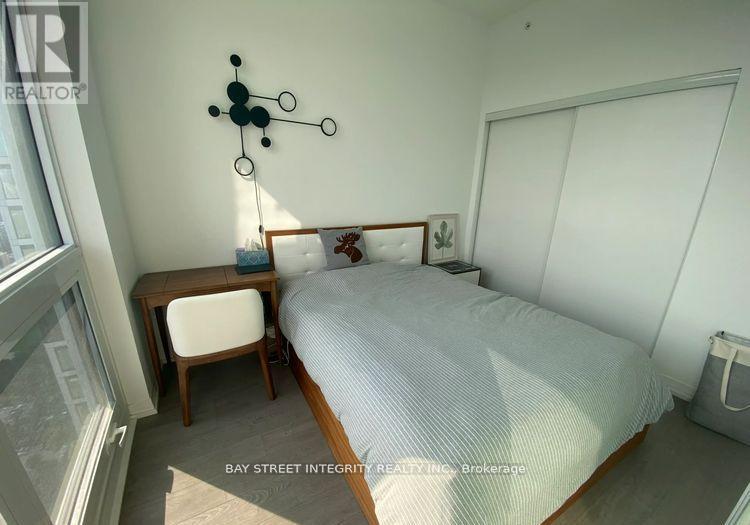 A bedroom with a bed, a chair, and a wall clock.