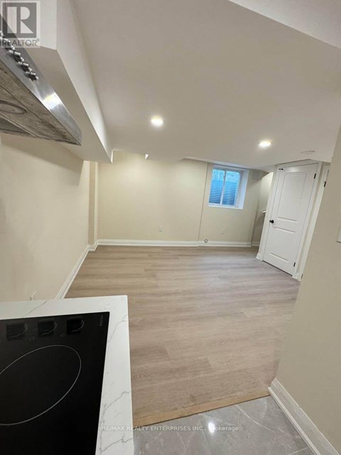 A kitchen with a black stove top oven and wooden flooring.