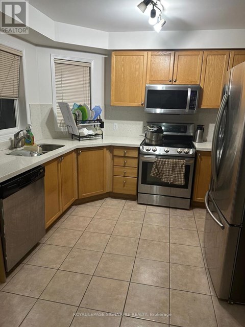 A kitchen with a refrigerator, oven, and microwave.