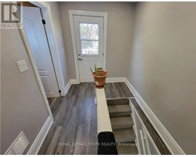 A hallway with a door and a plant on the steps.
