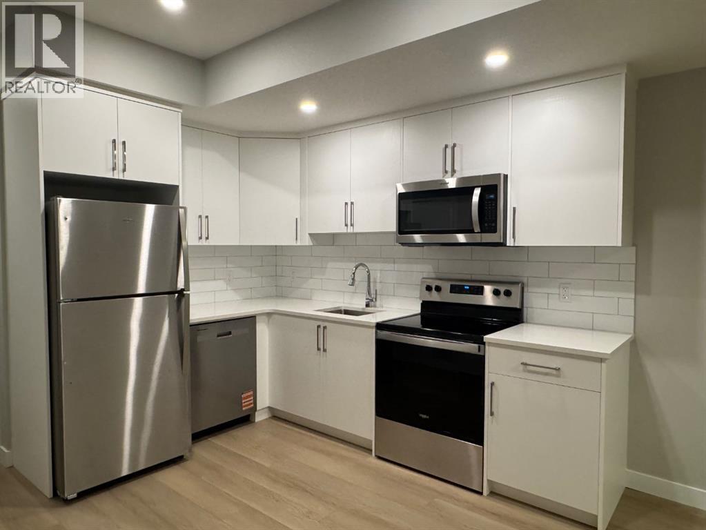 A modern kitchen with white cabinets and stainless steel appliances.