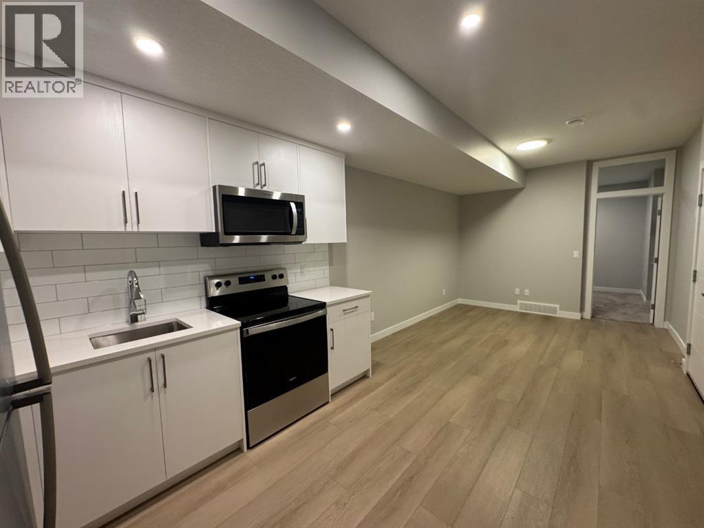 A kitchen with white cabinets and a black microwave.