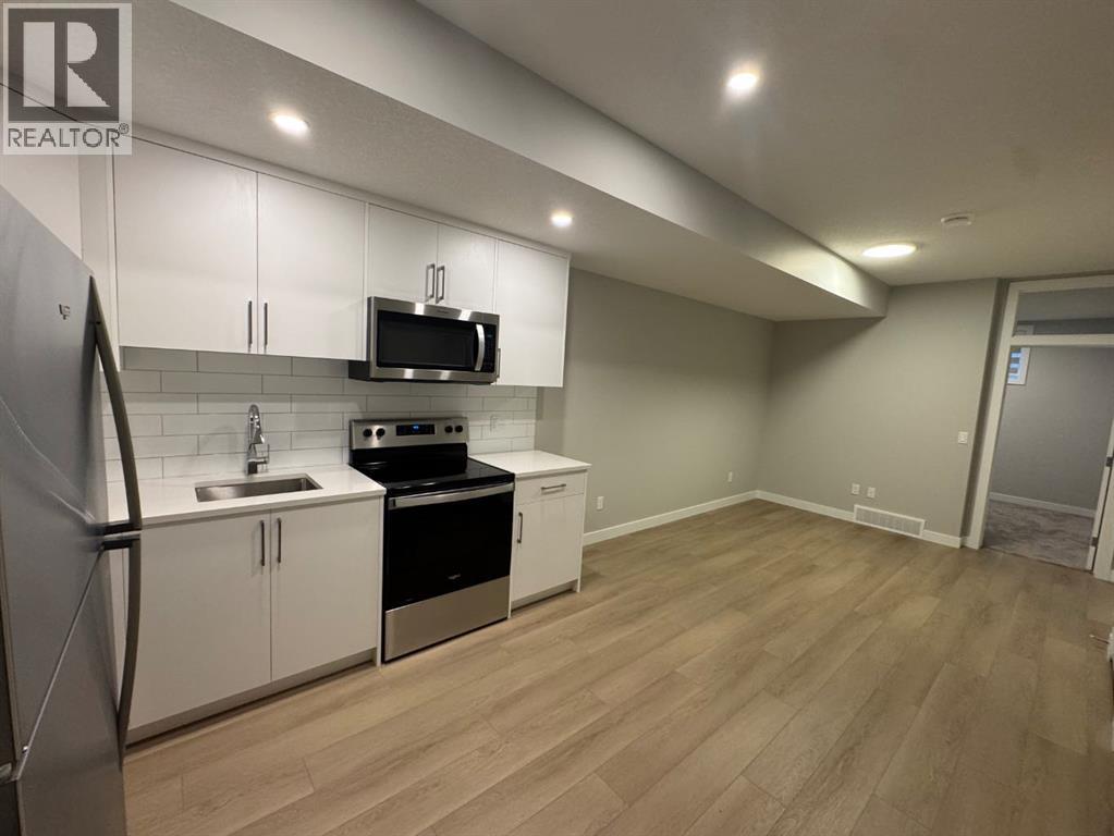 A kitchen with white cabinets and a wooden floor.