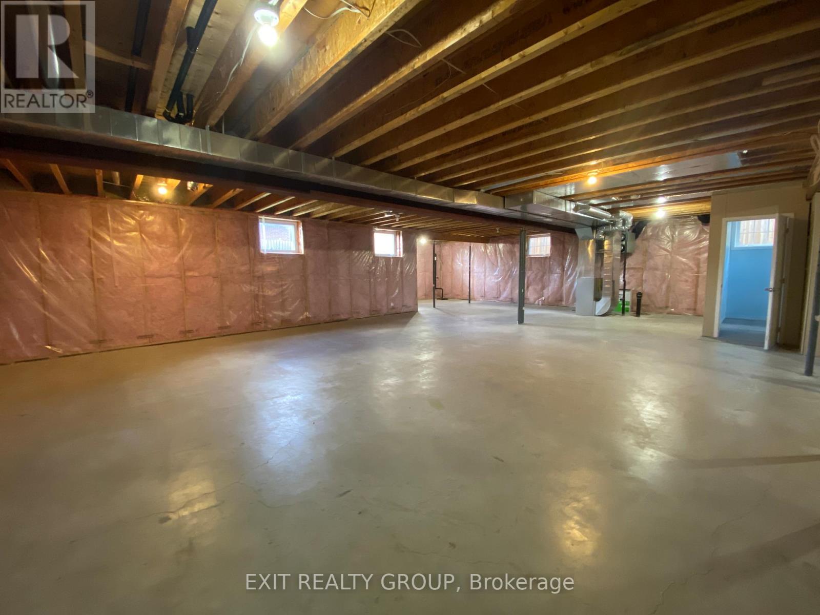 A spacious room with a polished concrete floor and exposed ceiling beams, currently under construction with insulation on the walls.