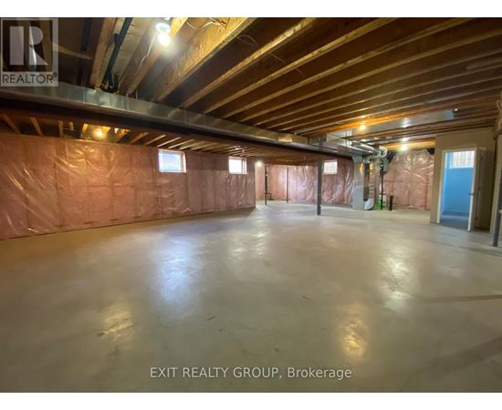 A spacious room with a polished concrete floor and exposed ceiling beams, currently under construction with insulation on the walls.