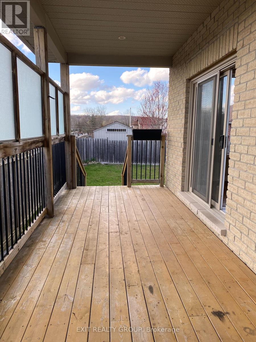 A wooden deck with a sliding glass door and a view of a fence and a house in the background.
