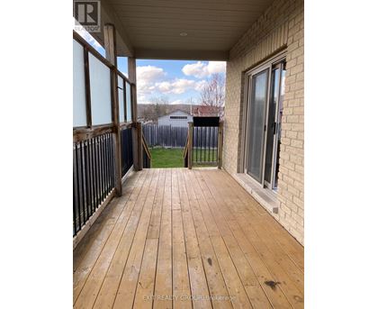 A wooden deck with a sliding glass door and a view of a fence and a house in the background.
