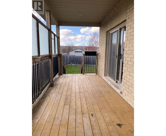 A wooden deck with a sliding glass door and a view of a fence and a house in the background.