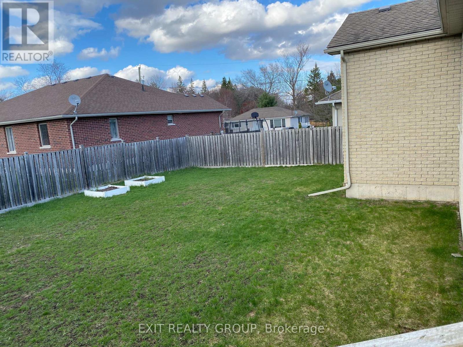 A backyard with a wooden fence and a house in the background.