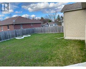 A backyard with a wooden fence and a house in the background.