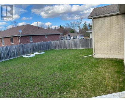 A backyard with a wooden fence and a house in the background.