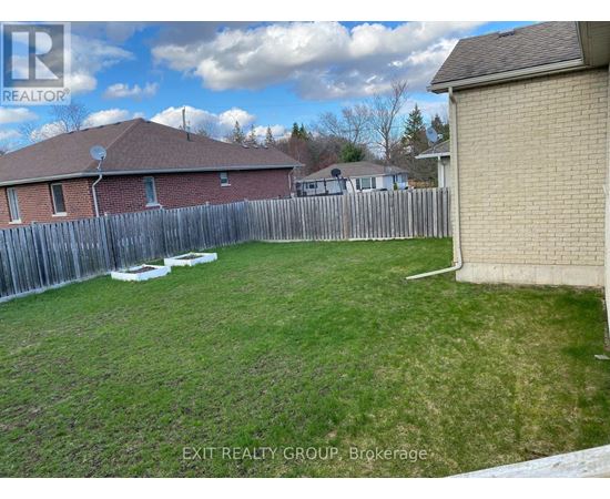 A backyard with a wooden fence and a house in the background.