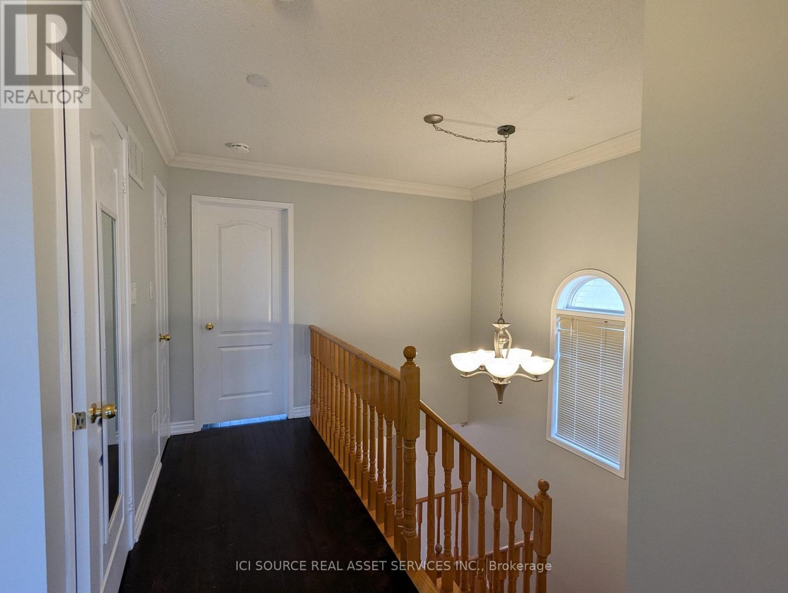 A hallway with a wooden staircase and a chandelier.