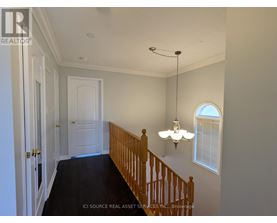 A hallway with a wooden staircase and a chandelier.