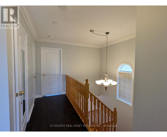 A hallway with a wooden staircase and a chandelier.