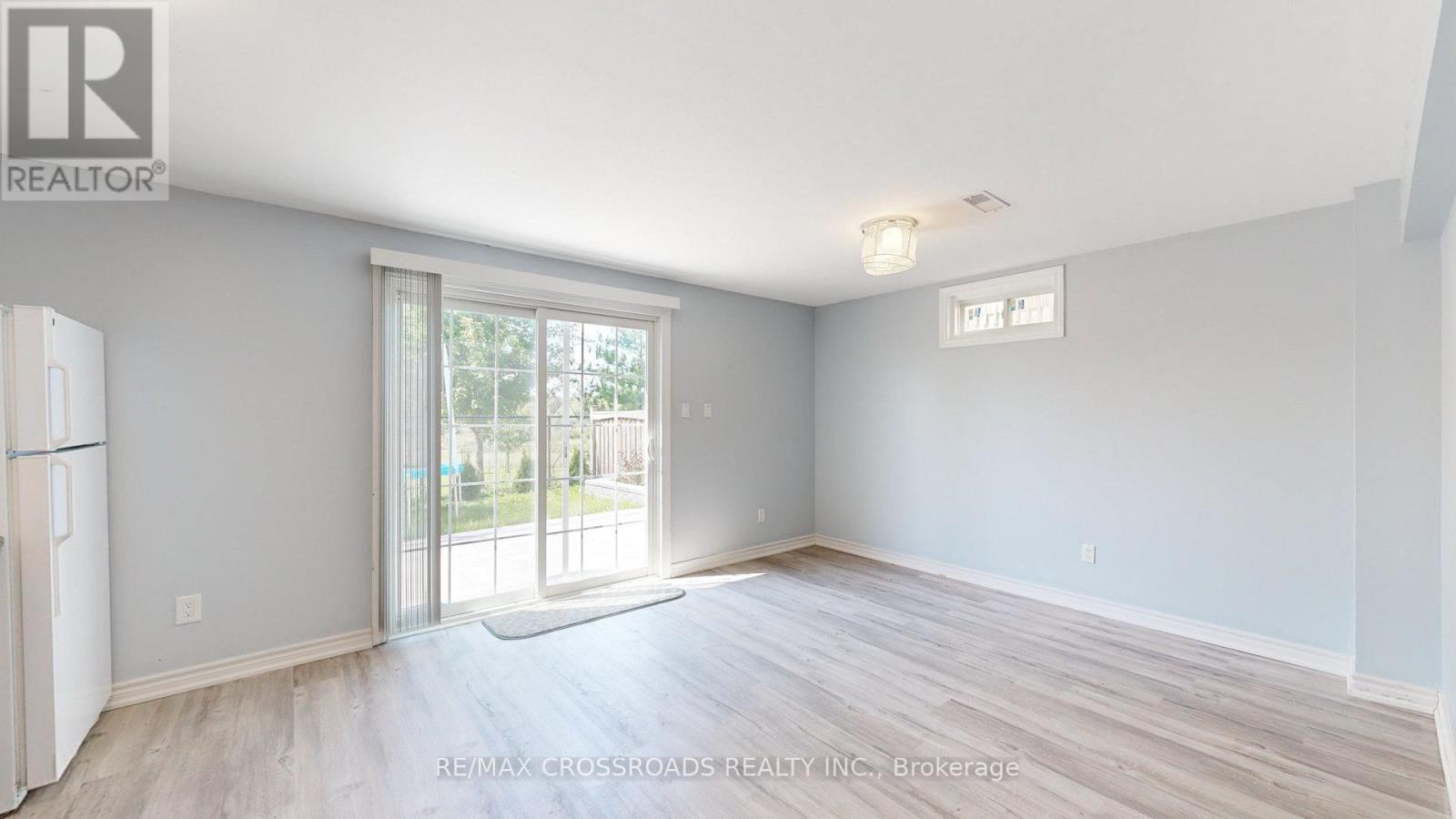 A spacious room with a sliding glass door leading to a balcony.