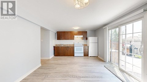 A kitchen with white appliances and wooden cabinets is shown in a real estate listing.
