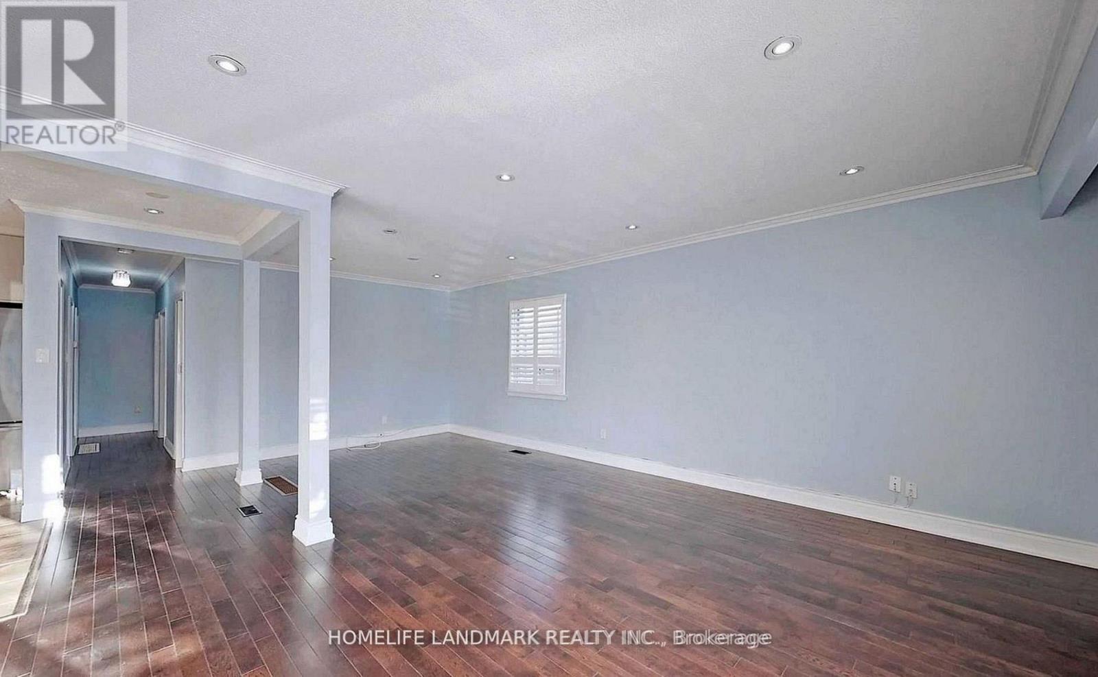 A spacious room with wooden flooring and a large window.