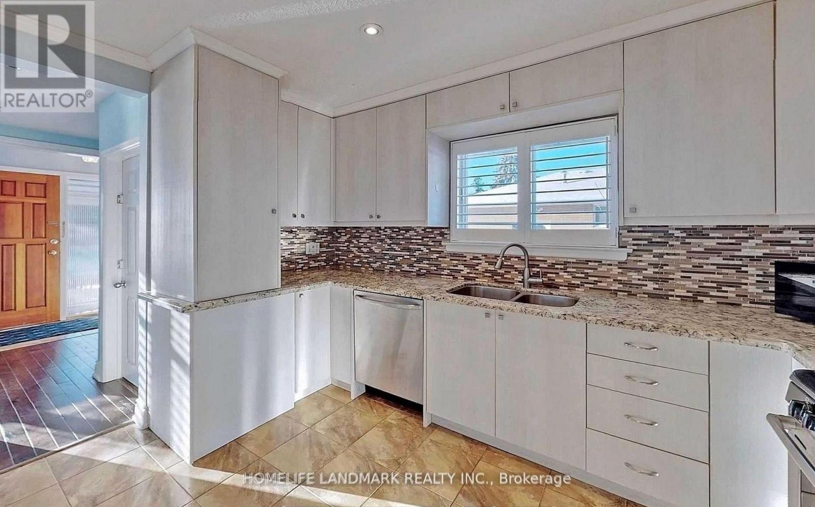 A kitchen with white cabinets and a stone backsplash.