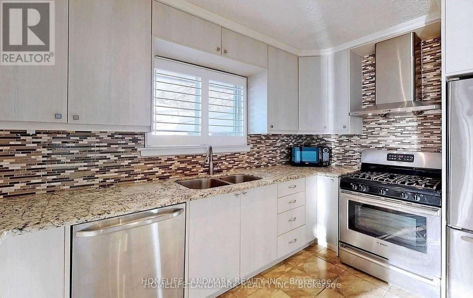 A kitchen with a stone backsplash and stainless steel appliances.