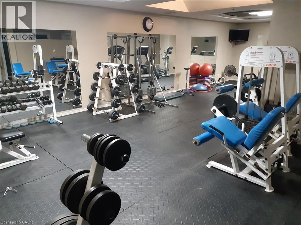 A gym with a variety of equipment including dumbbells, weight plates, and a bench press.