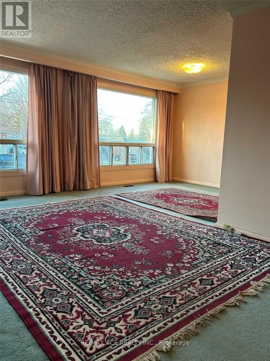A room with a rug on the floor and a window with curtains.
