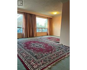 A room with a rug on the floor and a window with curtains.