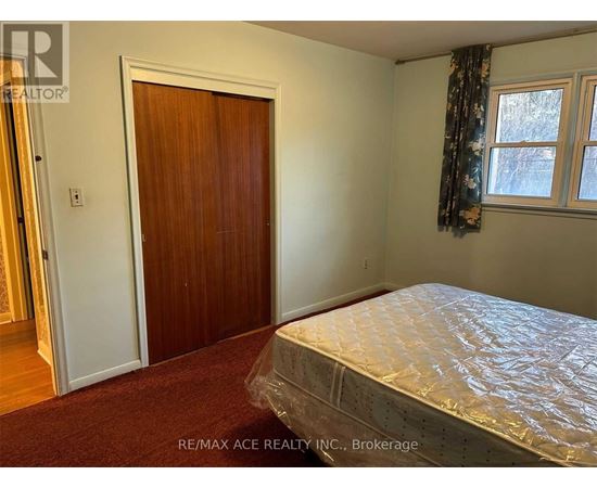 A bedroom with a bed covered in plastic, a door, and a window with curtains.