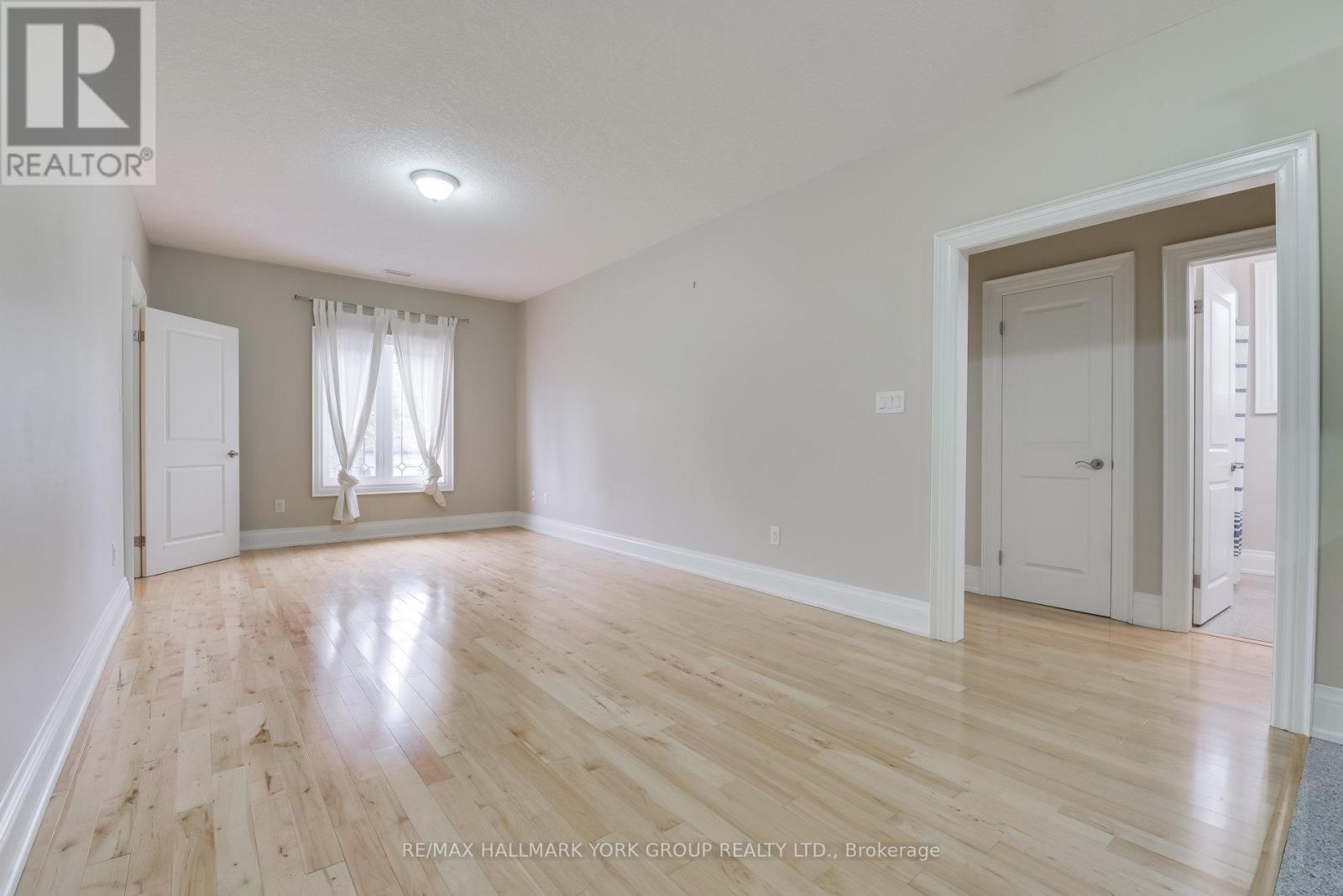 A spacious room with wooden flooring and white walls.
