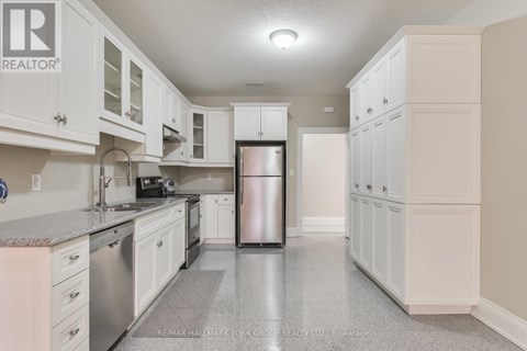 A kitchen with white cabinets and a refrigerator.