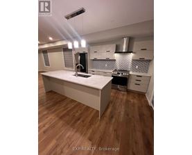 A modern kitchen with wooden floors and white cabinetry.