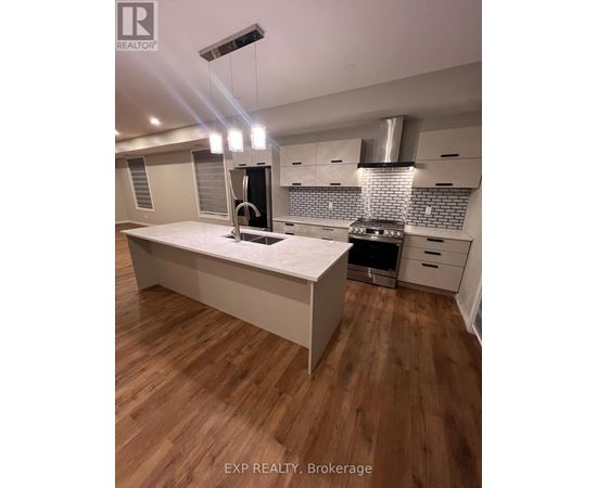 A modern kitchen with wooden floors and white cabinetry.