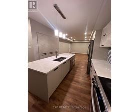 A modern kitchen with white cabinets and a wooden floor.