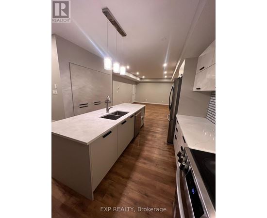 A modern kitchen with white cabinets and a wooden floor.