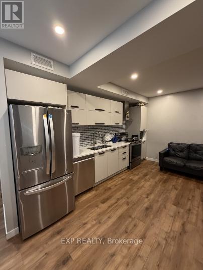 A modern kitchen with wooden floors and stainless steel appliances.