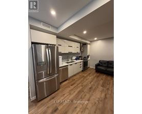 A modern kitchen with wooden floors and stainless steel appliances.