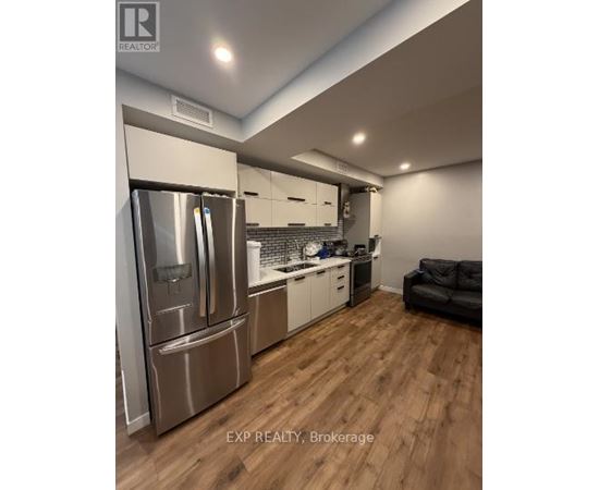 A modern kitchen with wooden floors and stainless steel appliances.