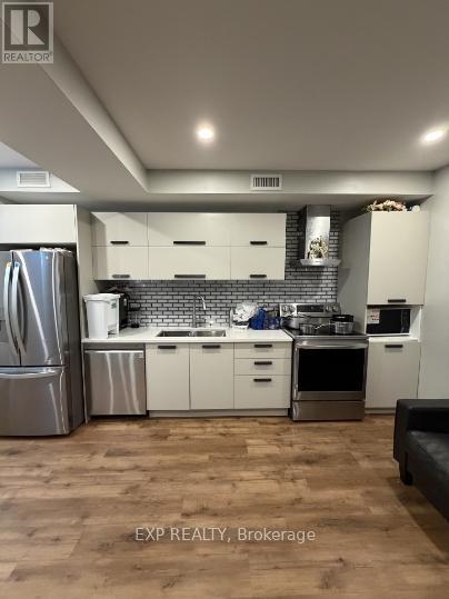 A kitchen with white cabinets and a wooden floor.