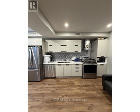 A kitchen with white cabinets and a wooden floor.