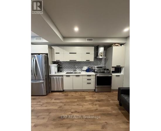 A kitchen with white cabinets and a wooden floor.