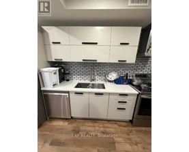 A kitchen with white cabinets and a brick backsplash.