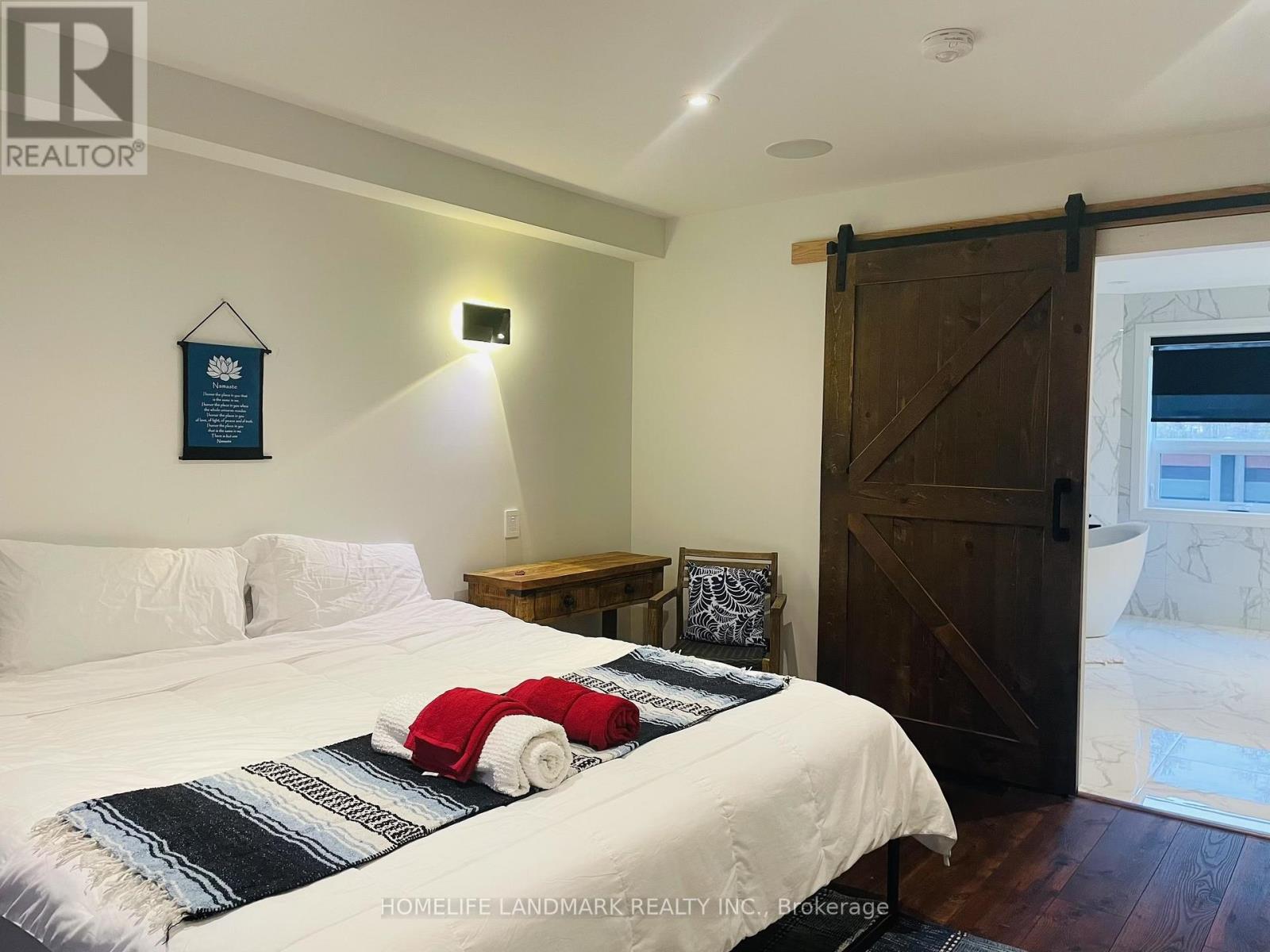 A bedroom with a bed, nightstand, and a door.