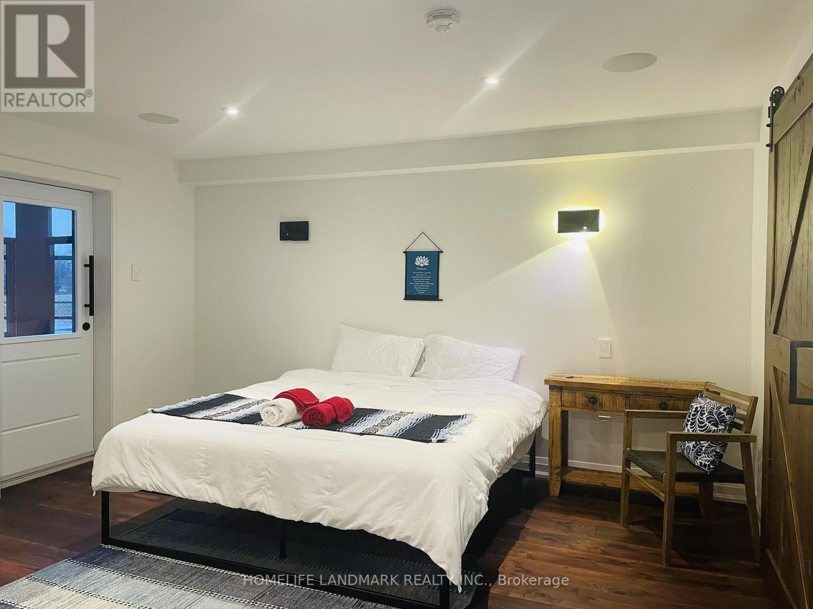 A bedroom with a bed, desk, chair, and a window.