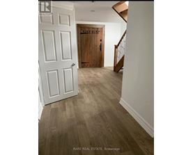 A hallway with a white door and a wooden door at the end.